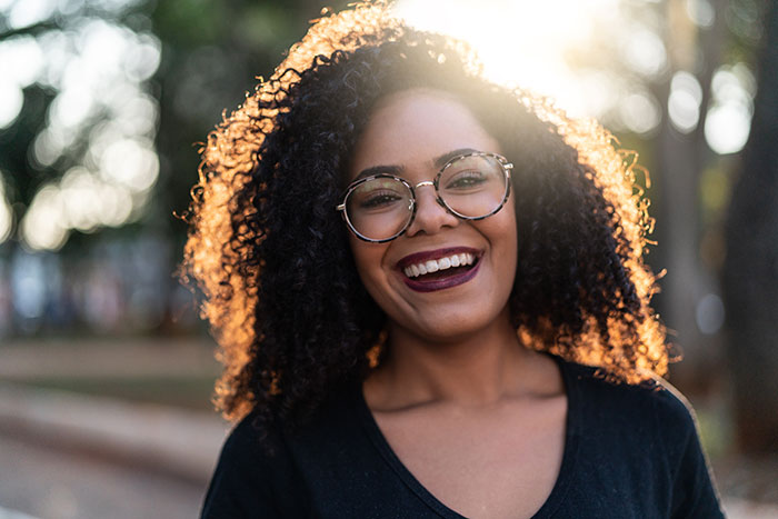 young woman smiles while standing in a park
